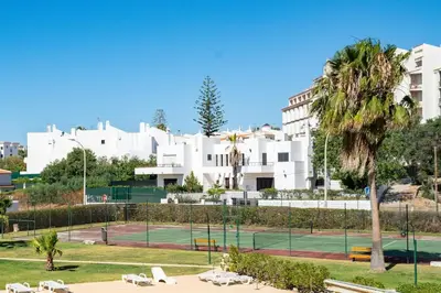a tennis court in front of a white building at SILCHORO - Estúdio remodelado com AC e piscina in Albufeira