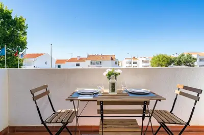 a table with two chairs and a vase of flowers on a balcony at SILCHORO - Estúdio remodelado com AC e piscina in Albufeira