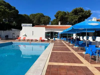 a swimming pool with chairs and umbrellas next to a building at Santa Fé in Albufeira