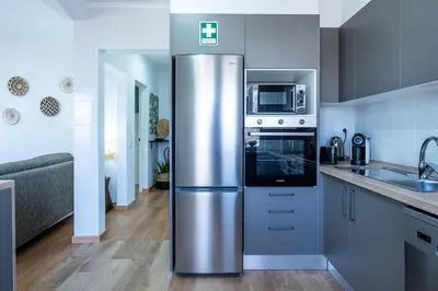 a stainless steel refrigerator in a kitchen next to a sink at Faro Center with AC & WiFi in Faro