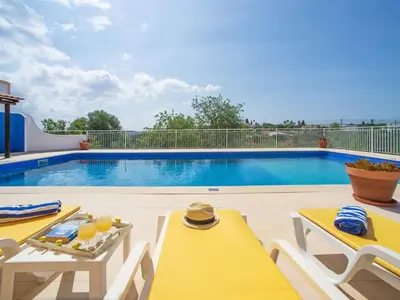 a pool with two chairs and a table with drinks on it at Holiday Home Sebastião by Interhome in Paderne