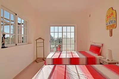 two beds in a room with two windows at Casa de Apra by Portucasa in Loulé