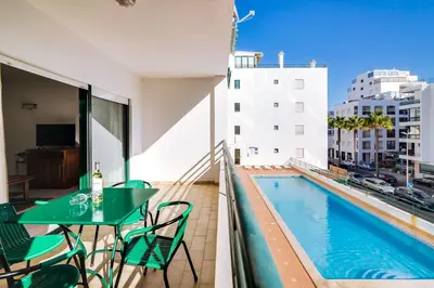 a balcony with a table and a swimming pool at AL - Apartamento Pérola in Quarteira