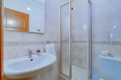a white bathroom with a sink and a shower at AL - Apartamento Pérola in Quarteira