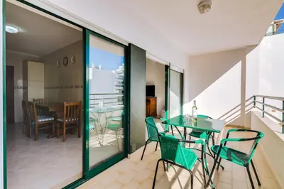 a balcony with a table and chairs and a dining room at AL - Apartamento Pérola in Quarteira