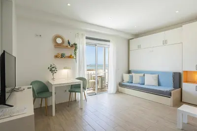 a kitchen with white cabinets and a refrigerator and a couch at Centralgarve - Stunning Beach Front Studio - Astro in Quarteira