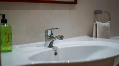 a white bathroom sink with a green bottle of soap at Albufeira Stylish Townhouse in Albufeira