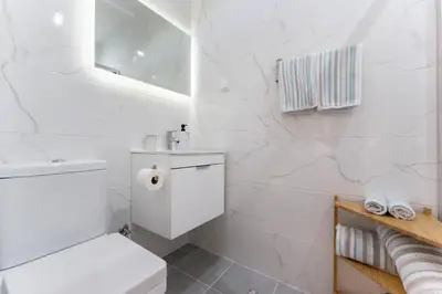a white bathroom with a toilet and a sink at Casa dos Sonhos Albufeira in Albufeira