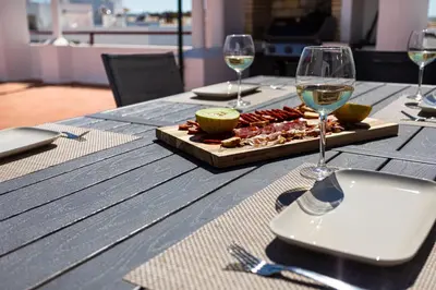 a wooden table with a plate of food and wine glasses at Centralgarve - Beachfront with Pool Penthouse in Quarteira