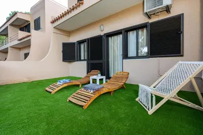 a patio with two chairs and a table on the grass at ALEGRIA 29 - T2 piso terreo com AC e piscina by My Algarve Rentals in Quarteira