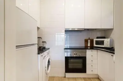 a kitchen with white cabinets and a stove and a microwave at ALEGRIA 29 - T2 piso terreo com AC e piscina by My Algarve Rentals in Quarteira