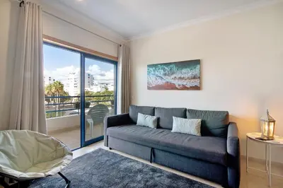 a living room with a couch and a large window at Lovely one bedroom apartment in Quarteira