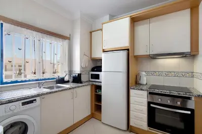 a kitchen with a white refrigerator and a dishwasher at Lovely one bedroom apartment in Quarteira