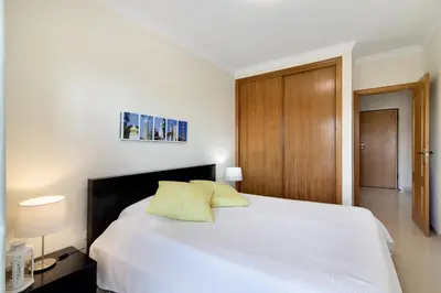 a bedroom with a white bed and a wooden door at Lovely one bedroom apartment in Quarteira