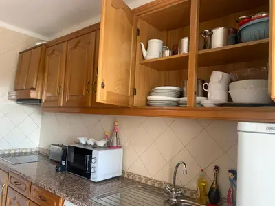 a kitchen with wooden cabinets and a microwave at Apartment 3 persons in Vilamoura, Algarve in Quarteira