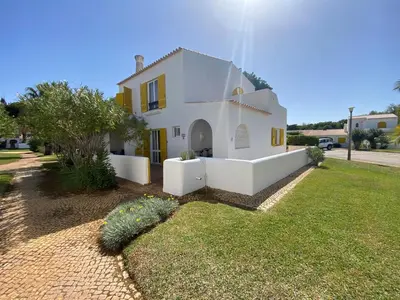 a white house with yellow doors and a yard at Aldeia do Golf O7 in Quarteira