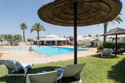 a swimming pool with chairs and an umbrella and a resort at Aldeia do Golf O7 in Quarteira
