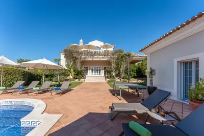 a patio with chairs and a swimming pool at Villa Breena - Quinta do Mar in Almancil