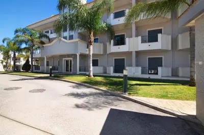 a large building with palm trees in front of it at Apartamento T1 - Em zona tranquila in Olhos de Água
