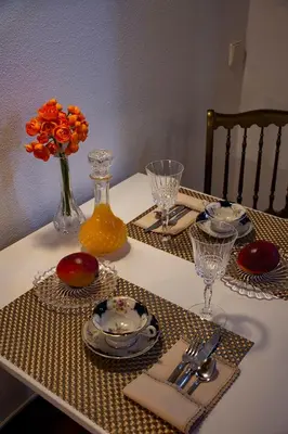 a table with plates and glasses and a vase with orange flowers at À dos Reis in Faro