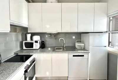 a kitchen with white cabinets and a sink and a microwave at Sun II - City center by HD PROPERTIES in Vilamoura