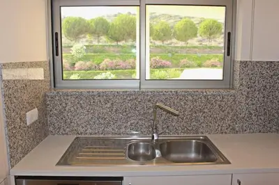 a kitchen counter with a sink and two windows at Apartment Amelo in Albufeira