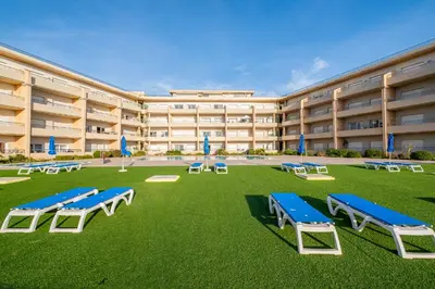 a large building with a lawn with blue and white benches at Apartment Oura - Views of sea, Albufeira bay & Old Town in Albufeira