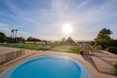 a large swimming pool on a patio with the ocean in the background at Apartment Oura - Views of sea, Albufeira bay & Old Town in Albufeira