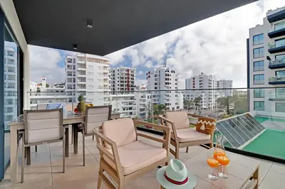 a balcony with a table and chairs and a view of a city at Sky Beach Apartment in Quarteira