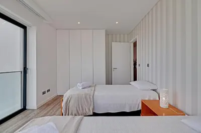 a white bedroom with two beds and a table at Sky Beach Apartment in Quarteira
