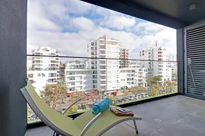 a balcony with a chair and a view of a city at Sky Beach Apartment in Quarteira