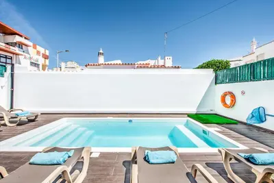 a swimming pool on the roof of a building with chairs at Villa Mitto in Albufeira