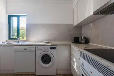 a kitchen with a washing machine and a sink at Salgados 1 Bedroom Apartment - 500m from the Beach in Guia