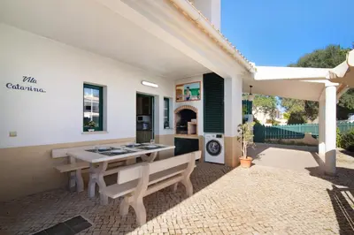 a patio with two benches and a table and a stove at Villa Catarina in Albufeira