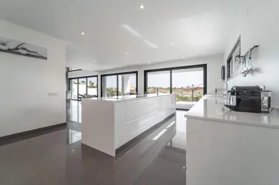 a kitchen with white counters and glass windows at Villa das Amendoeiras by HelloVacations in Albufeira