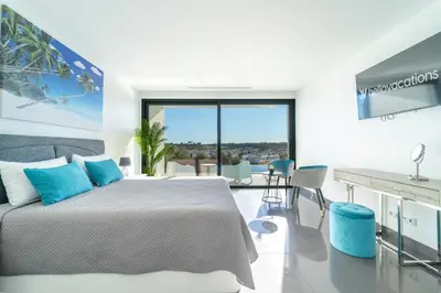 a white bedroom with a bed and a desk at Villa das Amendoeiras by HelloVacations in Albufeira