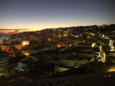 a view of a city at night with the ocean at Beachfront 2 bedroom apartment in Albufeira