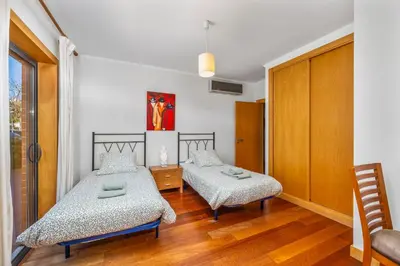 two beds in a room with wooden floors at Albufeira Corcovada Apartments in Albufeira