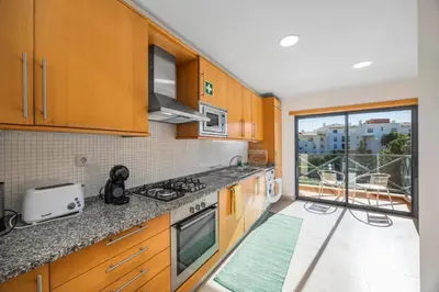 a kitchen with wooden cabinets and a view of a balcony at Albufeira Corcovada Apartments in Albufeira