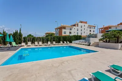 a swimming pool with chairs and a building at Albufeira Corcovada Apartments in Albufeira
