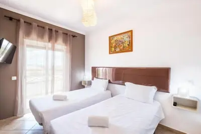 a bedroom with two beds and a tv and a window at Apartment Alfarmar - pool, beach only a few minutes away in Albufeira