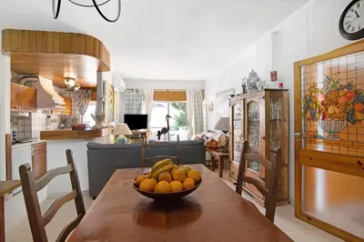 a kitchen and dining room with a bowl of fruit on a wooden table at T3 Duplex Albufeira in Olhos de Água