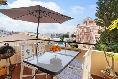 a table and chairs on a balcony with an umbrella at T3 Duplex Albufeira in Olhos de Água