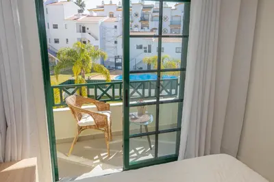 a room with a bed and a window with a chair at Holiday Albufeira in Albufeira