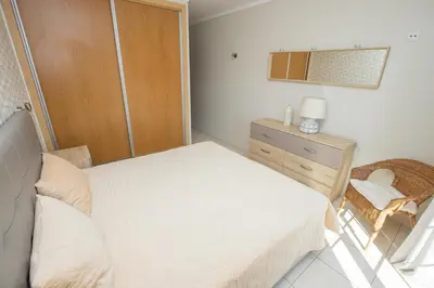 a bedroom with a bed and a dresser and a chair at Holiday Albufeira in Albufeira