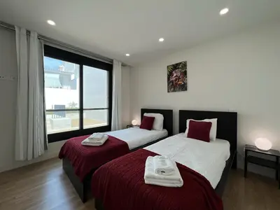 a bedroom with two beds with red sheets and a window at Faro Design 5 by Homing in Faro