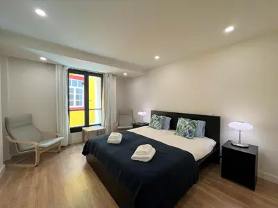 a bedroom with a bed and a chair and a window at Faro Design 5 by Homing in Faro