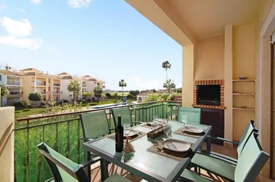 a dining room with a table and chairs on a balcony at Columbus Beach Apartment in Quarteira
