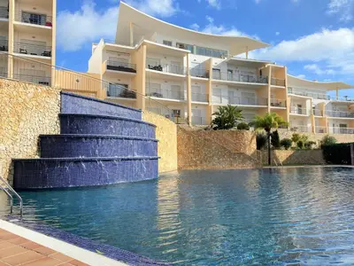 a swimming pool with a water fountain in front of a building at SeaViewSunset - Encosta da Orada in Albufeira