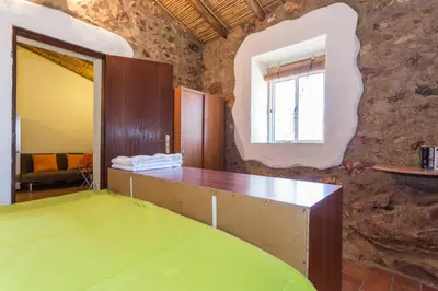 a room with a green bed and a stone wall at Casa Bi Rosario - Quinta Amoreira in Faro